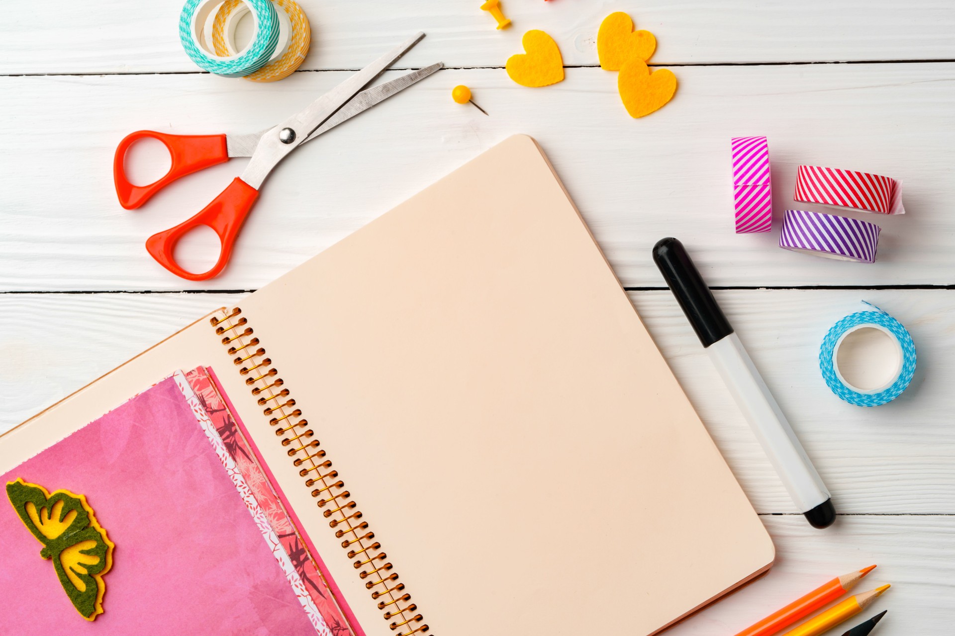 Creative workspace with open notebook, stationery, and decorative items on a wooden table